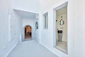 a hallway with white walls and windows in a house at Cave Suite Oia in Oia