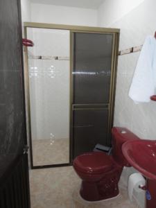 y baño con aseo rojo y ducha. en Hotel Los Paisas, en Mitú