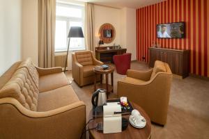 a living room with a couch and chairs and a table at Hotel Chemnitzer Hof in Chemnitz
