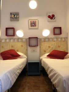 トレモリノスにあるArtas Apartamentosの赤い枕が付いたベッド2台が備わる客室です。