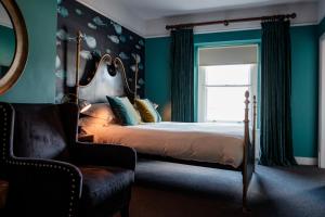 a bedroom with a bed and a chair and a window at The Bull Hotel in Bridport