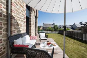 une terrasse avec une table, des chaises et un parasol dans l'établissement Le Ponant by Cocoonr, à Dinard