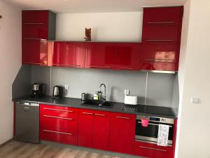 a kitchen with red cabinets and a sink at Apartament Emilia in Karwia