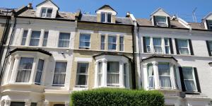 a large white house with windows and a hedge at Matheson Olympia Hotel in London