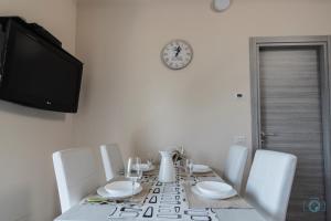 a dining room table with white chairs and a clock at Home Sweet Home Lakeview in Oggebbio