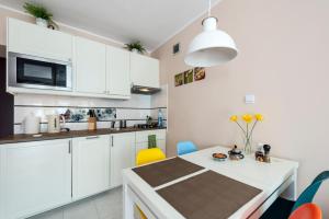 a kitchen with white cabinets and a table and chairs at Przytulny Apartament przy Teatrze Wielkim in Warsaw