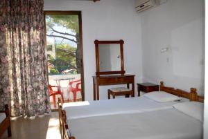 a bedroom with a bed and a mirror and a window at Anthula Sun in Archangelos