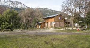 una casa de madera con una montaña en el fondo en Hostel Los Coihues en San Carlos de Bariloche