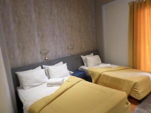 2 letti in una camera con lenzuola gialle di Nafsika Hotel Athens Centre ad Atene