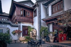a house with a table and chairs in front of it at Shaxi Aoding Courtyard in Jianchuan