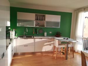 uma cozinha verde com armários brancos e uma mesa em Residenza San Pietro em Vicenza