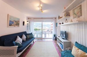ein Wohnzimmer mit einem blauen Sofa und einem TV in der Unterkunft Lets Holidays apartment Sa Coma 2 in Tossa de Mar