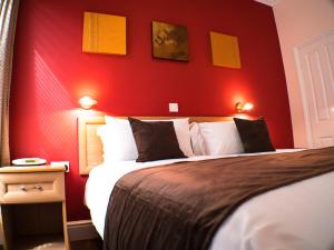 a bedroom with a red wall with a bed at Glen Mona in Douglas