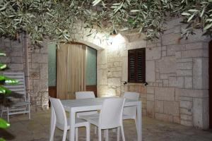 a white table and chairs in front of a stone wall at Dimora Domrose in Locorotondo