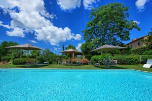 a swimming pool with umbrellas and a house at Villa Sonia by PosarelliVillas in San Donato in Poggio