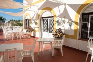 un restaurante con mesas blancas y sillas en una terraza en Hotel Agades, en San José