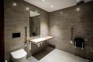 W łazience znajduje się umywalka, toaleta i lustro. w obiekcie The Residence Hotel at The Nottinghamshire Golf & Country Club w Nottingham