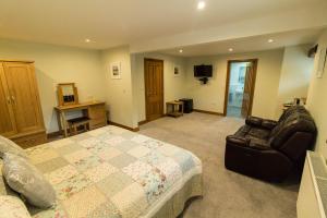 a bedroom with a bed and a couch and a chair at Lords Seat Bed & Breakfast in Keswick