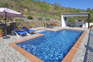 a swimming pool with two chairs and an umbrella at Villa La Hoya in Tijarafe