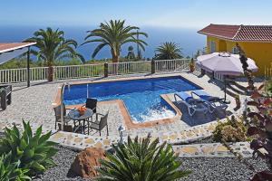 a pool with a table and chairs and a house at Villa La Hoya in Tijarafe