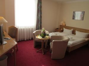 a hotel room with a bed and a table and chairs at Hotel Flora in Fredersdorf