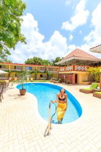 una mujer con un vestido amarillo de pie junto a una piscina en Sunset Shores Beach Hotel, en Kingstown