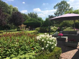 a garden with a couch and an umbrella and flowers at De Tuinkamer in Ter Apel