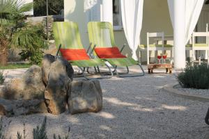 two green and red chairs and rocks in a yard at Villa Mandolina Apartments in Zadar