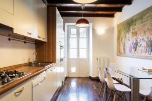 a kitchen with white cabinets and a table with chairs at Palazzo Del Pero Luxury Attic - byMyHomeinComo in Como