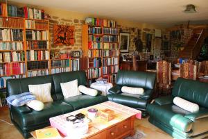 ein Wohnzimmer mit zwei grünen Ledersofas und Bücherregalen in der Unterkunft Ti Er Mad in Kernascléden