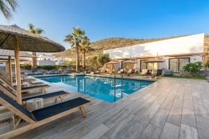 una piscina con sillas, una sombrilla y una casa en Aggello Boutique Hotel, en Stalida