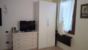 a bedroom with a dresser with a television and a window at B&B Martina in Agugliaro