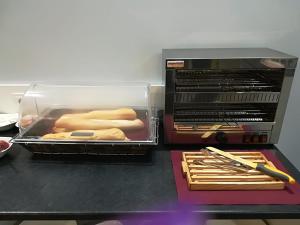 a toaster oven with hot dogs and tongs on a counter at Hotel Río Asón in Ramales de la Victoria
