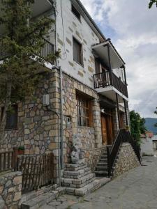 une vieille maison en pierre avec des escaliers et un balcon. dans l'établissement Agios Achillios, à Agios Achillios