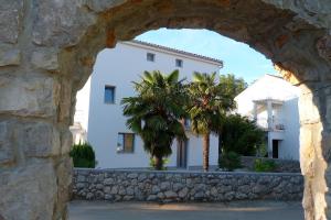 an archway in front of a white building with palm trees at Apartments Monja & Dadi in Vantačići