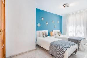 - 2 lits dans une chambre avec un mur bleu dans l'établissement Soho Riverside Suite Málaga, à Malaga