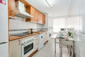 - une cuisine avec des appareils blancs et des armoires en bois dans l'établissement Soho Riverside Suite Málaga, à Malaga