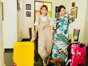 two women are standing next to luggage and a dog at Ceylon Pearlwing Resort in Negombo