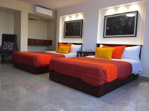 2 Betten in einem Hotelzimmer mit orangefarbenen und gelben Kissen in der Unterkunft Hotel Santa Lucia del Bosque in San Luis Potosí