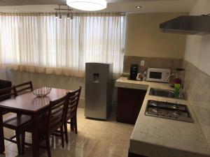 cocina con mesa y cocina con fogones y nevera en Hotel Santa Lucia del Bosque, en San Luis Potosí