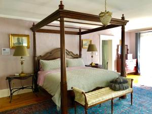 a bedroom with a canopy bed and a bench at 1000 Islands Bed and Breakfast-The Bulloch House in Gananoque