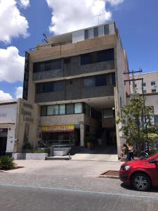 un bâtiment avec une voiture rouge garée devant lui dans l'établissement Hotel Santa Lucia del Bosque, à San Luis Potosí