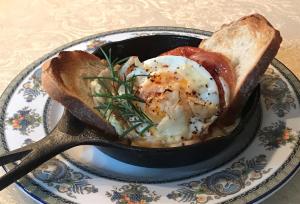 a bowl of eggs and bread on a plate with a spoon at Parsonage Inn Bed and Breakfast in Saint Michaels