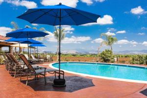 una piscina con sillas y sombrillas y una piscina en Carter Estate Winery and Resort, en Temecula
