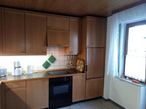 a kitchen with wooden cabinets and a black appliance at Haus Stefanie in Niederburg