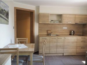 a kitchen with wooden cabinets and a table with chairs at Penzion Šléglov in Šleglov