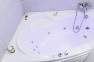 uma banheira branca com um chuveiro na casa de banho em Studio Suite near Lake with Jacuzzi em Sumy