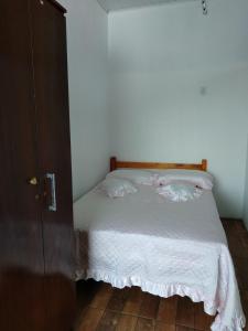 a bedroom with a bed with white sheets at Hospedagem Navegantes in Navegantes