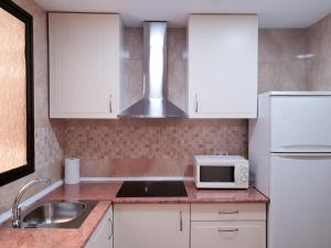 a kitchen with white cabinets and a sink and a microwave at Valencia Gold Beach in Valencia