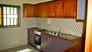 a kitchen with wooden cabinets and a stove and a sink at Villa Beach Avepozo Lome in Lomé